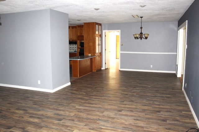 interior space featuring a textured ceiling, hanging light fixtures, dark wood-type flooring, and a notable chandelier