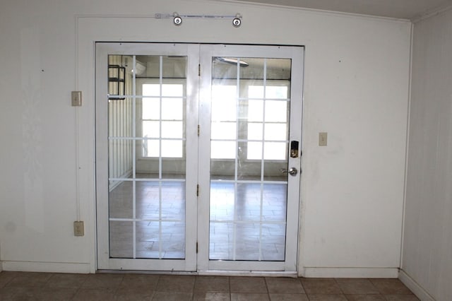 doorway to outside featuring crown molding, dark tile patterned flooring, and vaulted ceiling