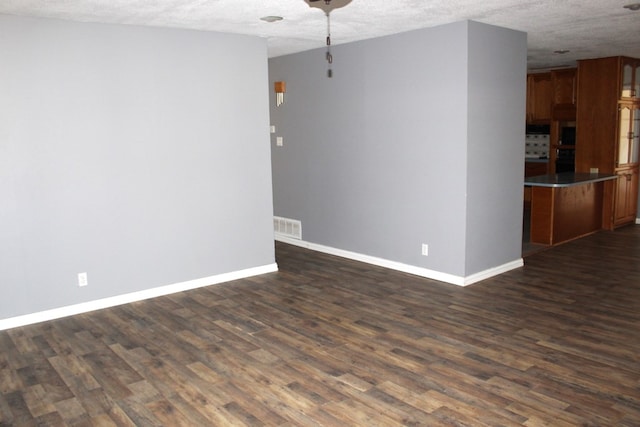 unfurnished room with dark hardwood / wood-style flooring and a textured ceiling