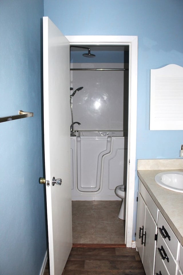 bathroom with a shower, hardwood / wood-style floors, vanity, and toilet