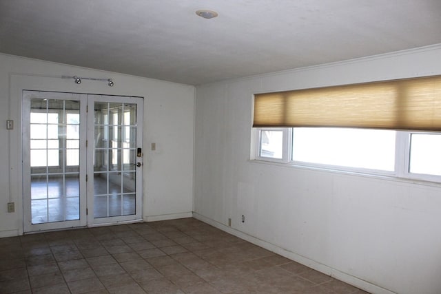 spare room with a healthy amount of sunlight, dark tile patterned floors, and ornamental molding