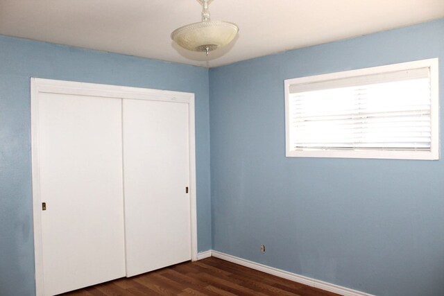 unfurnished bedroom featuring a closet and dark wood-type flooring