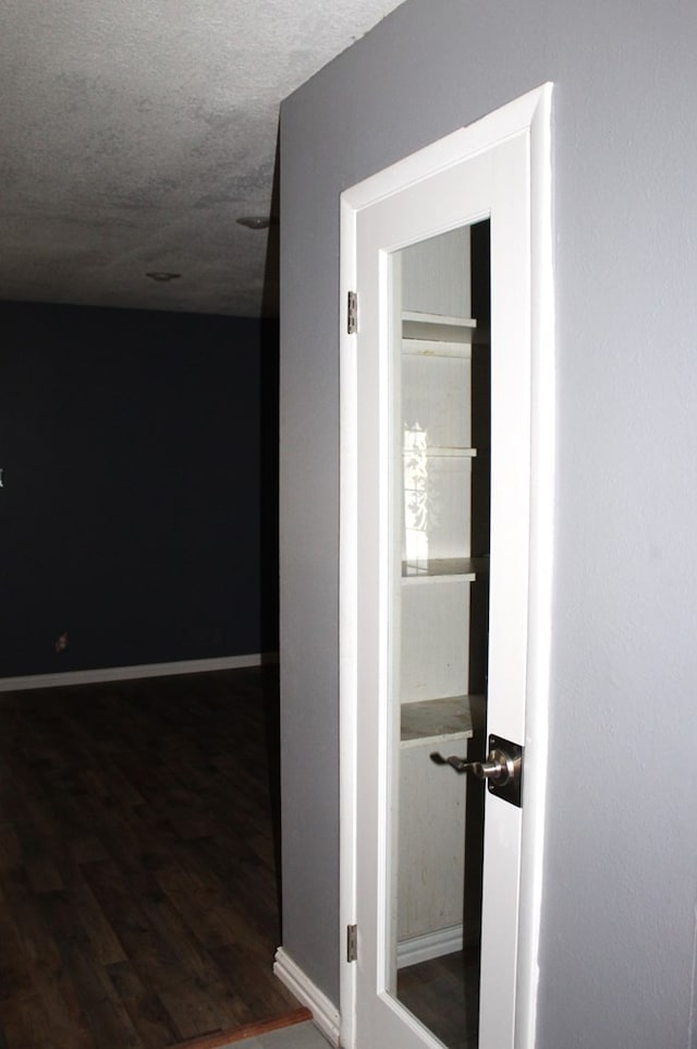 corridor with dark hardwood / wood-style flooring and a textured ceiling