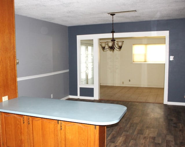 kitchen with plenty of natural light, dark hardwood / wood-style floors, decorative light fixtures, and an inviting chandelier