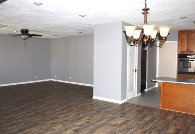 kitchen with dark hardwood / wood-style flooring, ceiling fan with notable chandelier, pendant lighting, and a textured ceiling