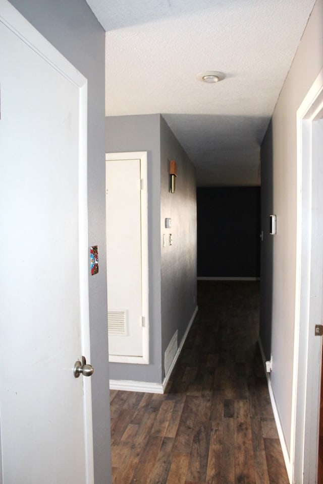 hallway featuring a textured ceiling and dark hardwood / wood-style flooring