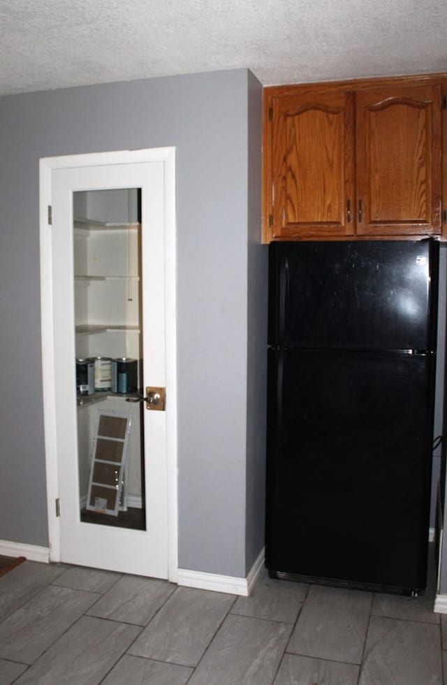 kitchen with black fridge and a textured ceiling