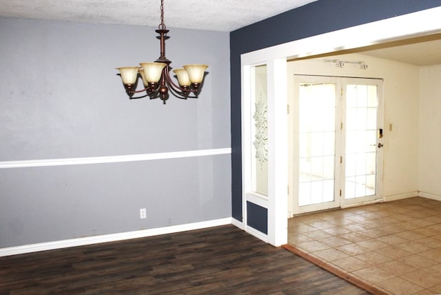 interior space featuring french doors, dark hardwood / wood-style floors, a notable chandelier, a textured ceiling, and lofted ceiling