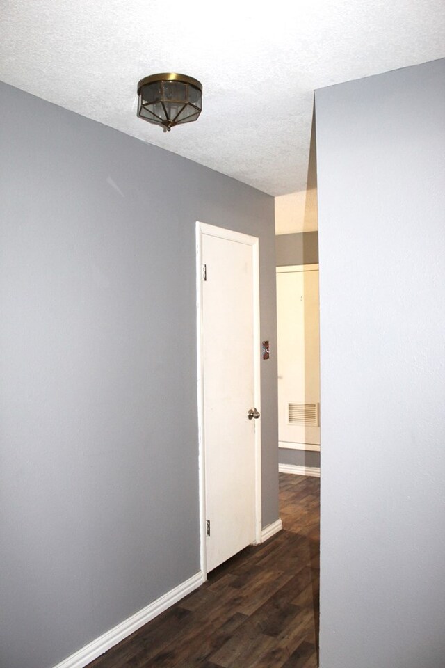 hall with dark hardwood / wood-style flooring and a textured ceiling