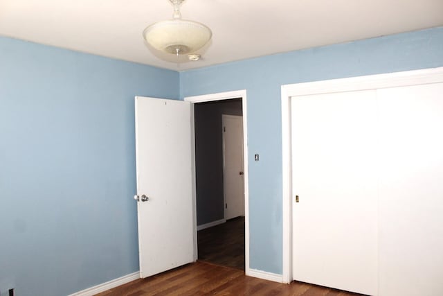 unfurnished bedroom with a closet and dark wood-type flooring