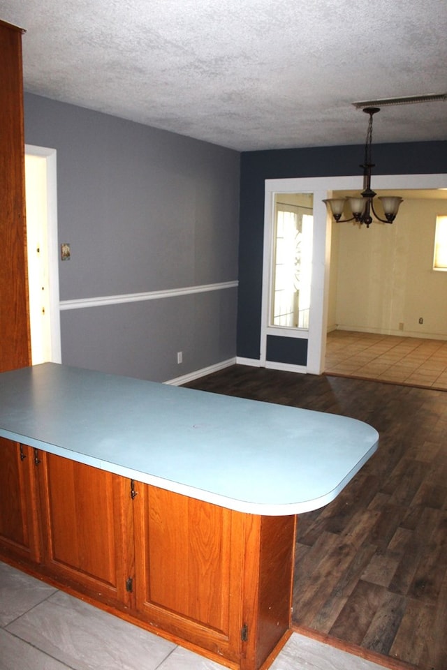 interior space with a notable chandelier, light wood-type flooring, and a textured ceiling