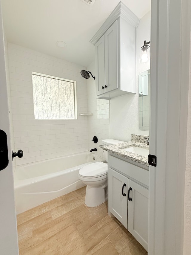 full bathroom featuring hardwood / wood-style floors, vanity, toilet, and tiled shower / bath combo