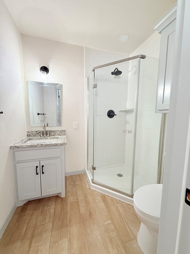 bathroom with hardwood / wood-style flooring, vanity, toilet, and walk in shower