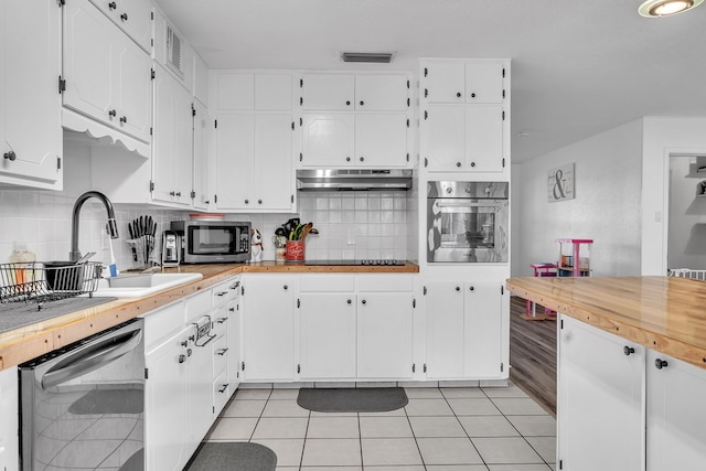2108 Cecilia, Big Spring, TX 79720 - kitchen featuring appliances with stainless steel finishes, under cabinet range hood, white cabinetry, light countertops, and light tile patterned flooring