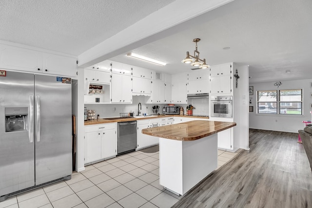 2108 Cecilia, Big Spring, TX 79720 - kitchen with appliances with stainless steel finishes, butcher block counters, white cabinetry, a chandelier, and a textured ceiling