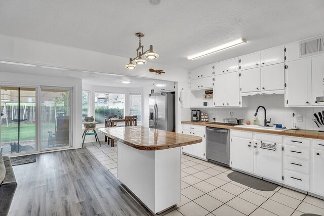 2108 Cecilia, Big Spring, TX 79720 - kitchen with appliances with stainless steel finishes, butcher block countertops, white cabinetry, tasteful backsplash, and a textured ceiling