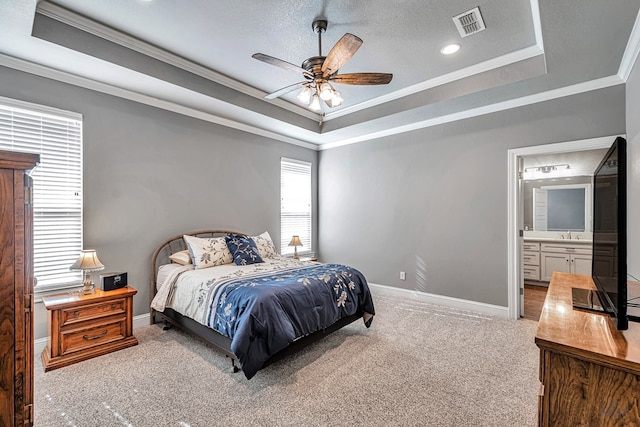 bedroom with ceiling fan, ensuite bath, ornamental molding, and a raised ceiling