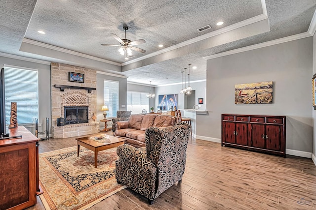 living room featuring ornamental molding, a fireplace, and a tray ceiling