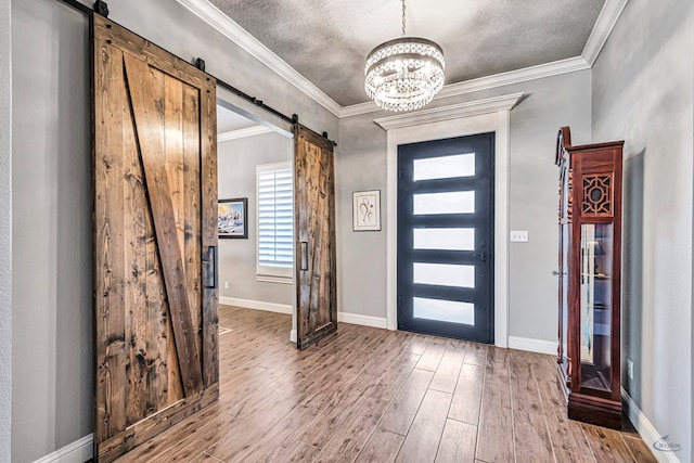 entryway featuring a textured ceiling, crown molding, a barn door, and an inviting chandelier