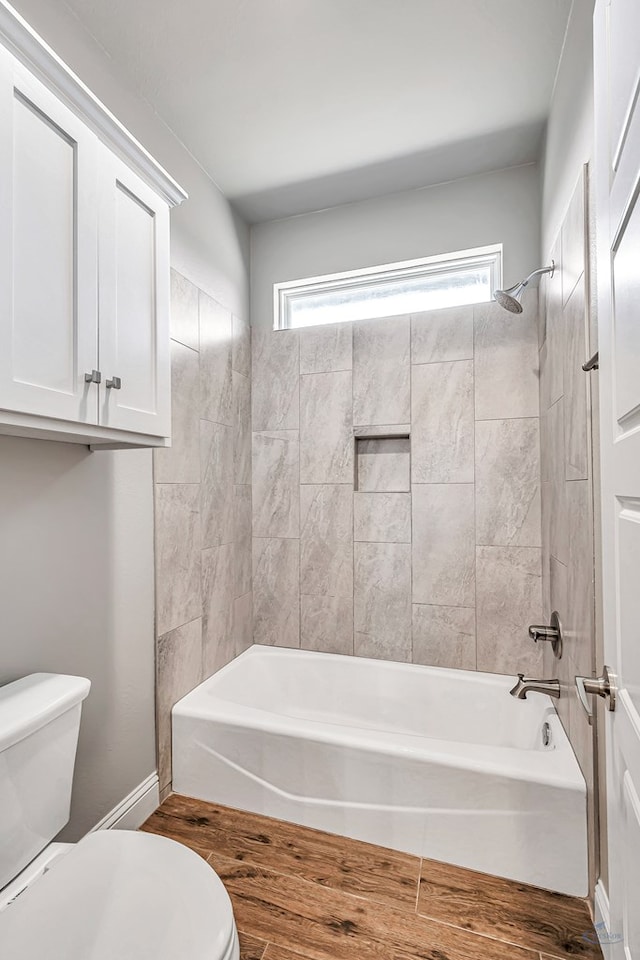 bathroom with a wealth of natural light, toilet, and tiled shower / bath