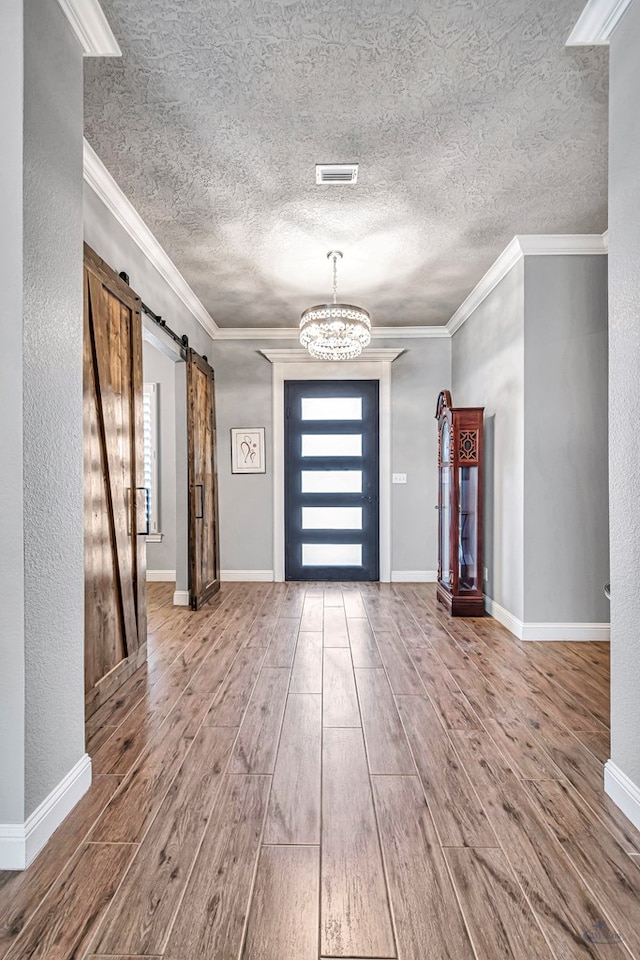 foyer featuring ornamental molding, a barn door, and a chandelier