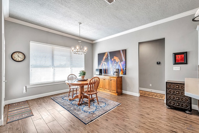 dining area with an inviting chandelier, ornamental molding, and a textured ceiling