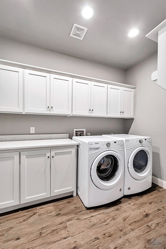 laundry room featuring cabinets, light hardwood / wood-style flooring, and washing machine and clothes dryer