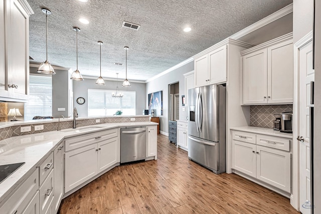 kitchen featuring stainless steel appliances, tasteful backsplash, pendant lighting, white cabinets, and sink