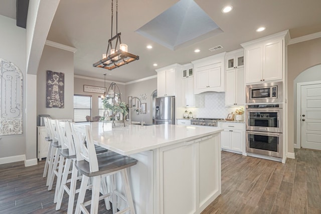 kitchen featuring visible vents, an island with sink, glass insert cabinets, stainless steel appliances, and light countertops