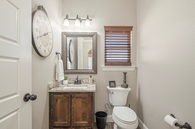 half bathroom with toilet, vanity, and baseboards