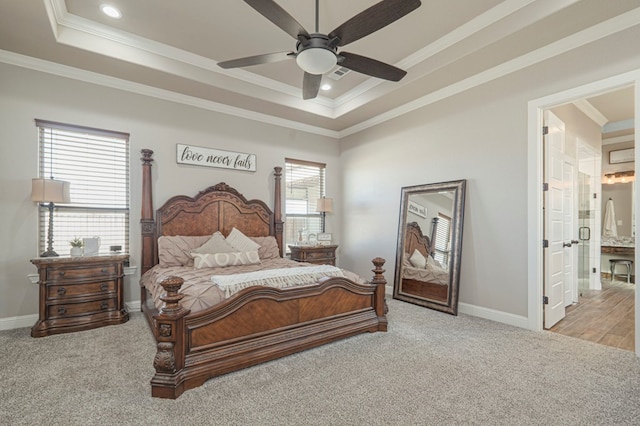 bedroom featuring ornamental molding, a tray ceiling, light carpet, and baseboards