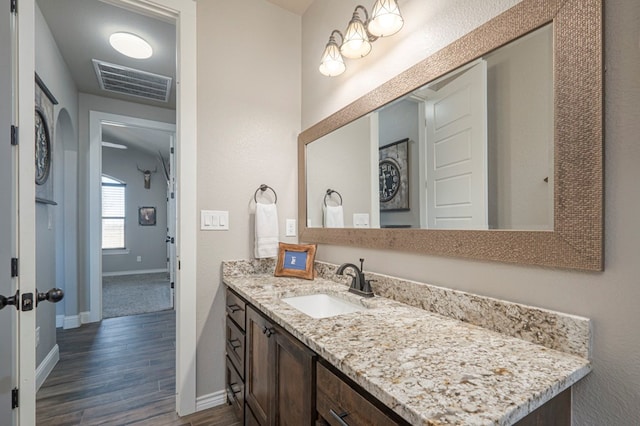 bathroom with wood finished floors, vanity, visible vents, and baseboards