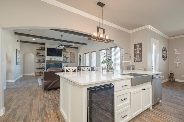 kitchen featuring decorative light fixtures, beverage cooler, open floor plan, light countertops, and a center island with sink