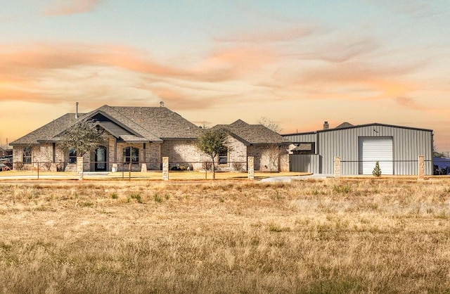 french country style house with a detached garage, fence, and an outbuilding