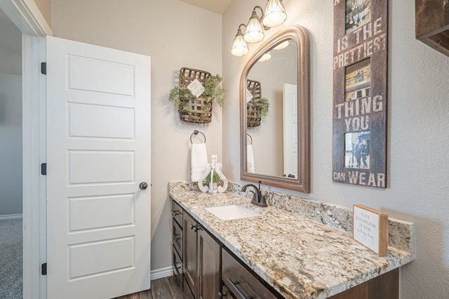 bathroom featuring vanity, baseboards, and wood finished floors