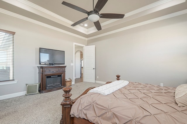 carpeted bedroom featuring arched walkways, ornamental molding, a glass covered fireplace, a ceiling fan, and baseboards