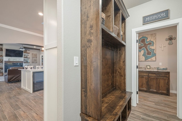 mudroom with ornamental molding, a fireplace, a ceiling fan, and wood tiled floor