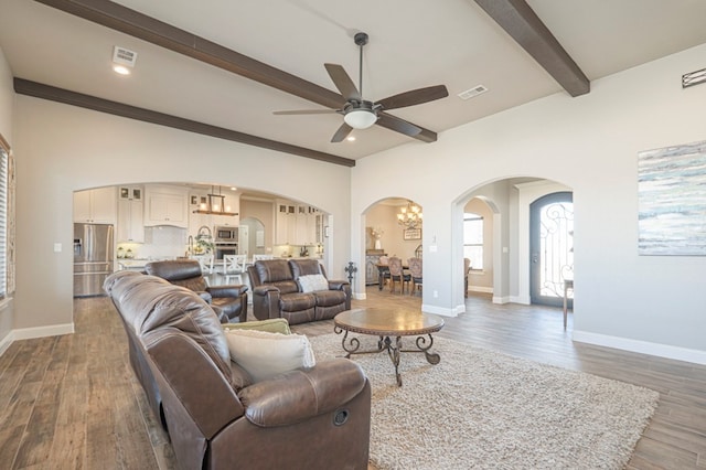 living area featuring beam ceiling, dark wood-type flooring, visible vents, and baseboards