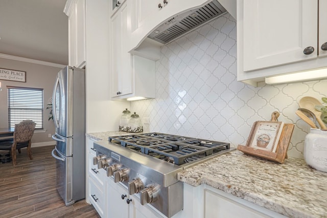 kitchen featuring custom range hood, appliances with stainless steel finishes, ornamental molding, light stone countertops, and white cabinetry