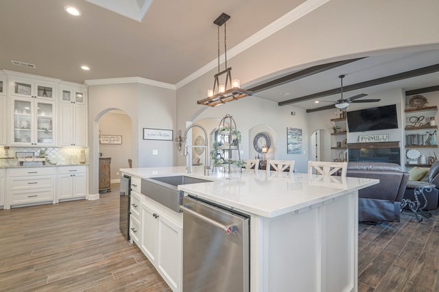 kitchen with arched walkways, open floor plan, white cabinetry, and stainless steel dishwasher