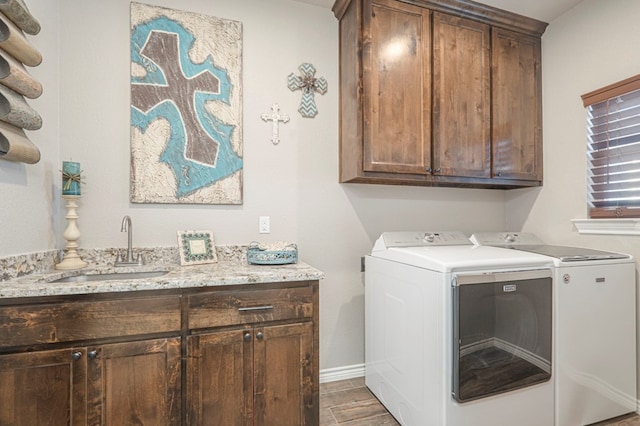 laundry room featuring wood finished floors, a sink, baseboards, washer and dryer, and cabinet space