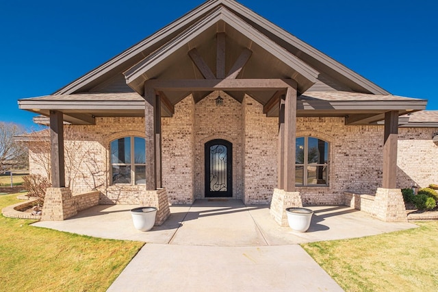 doorway to property featuring brick siding and a lawn