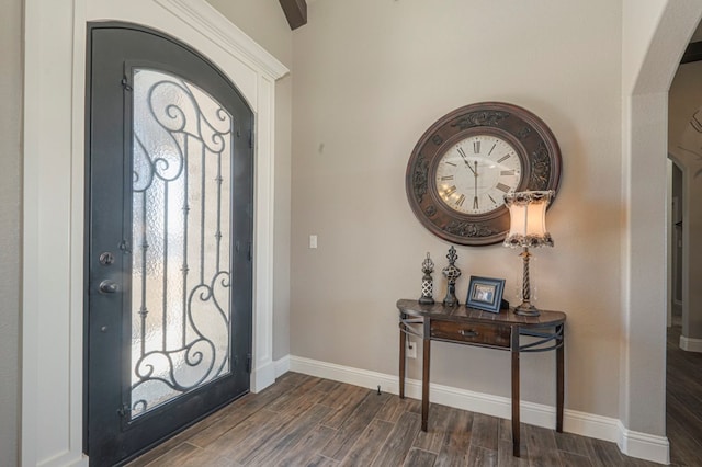 entryway with arched walkways, wood finish floors, and baseboards