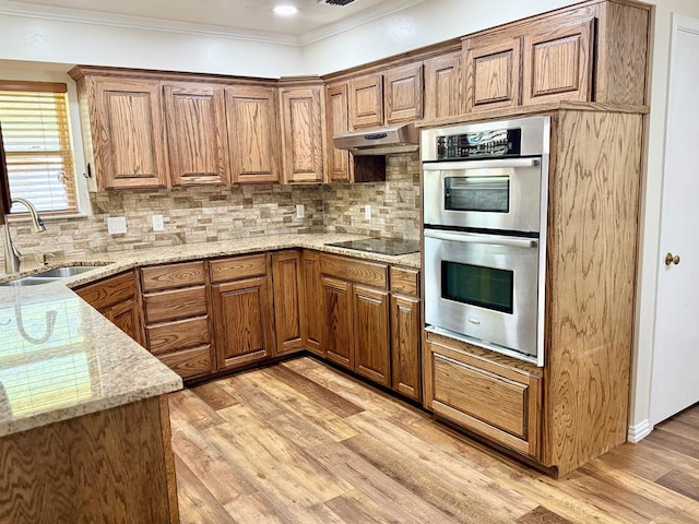 3612 Oakridge Dr, Midland, TX 79707 - kitchen featuring double oven, black electric cooktop, ornamental molding, light wood-style flooring, and light stone countertops