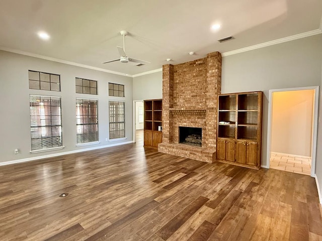 3612 Oakridge Dr, Midland, TX 79707 - unfurnished living room featuring a ceiling fan, crown molding, wood finished floors, and a brick fireplace