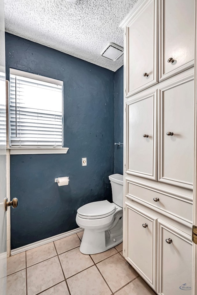 bathroom with a textured ceiling, tile patterned floors, and toilet