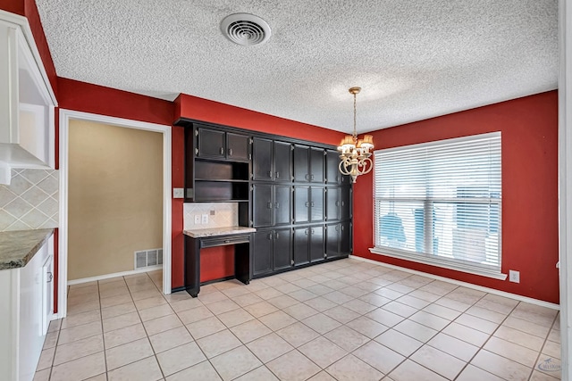 kitchen featuring hanging light fixtures, tasteful backsplash, light tile patterned flooring, and an inviting chandelier