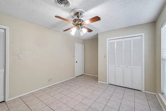 unfurnished bedroom with light tile patterned flooring, ceiling fan, a closet, and a textured ceiling