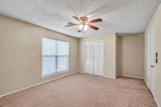 unfurnished bedroom featuring ceiling fan, carpet, a textured ceiling, and a closet