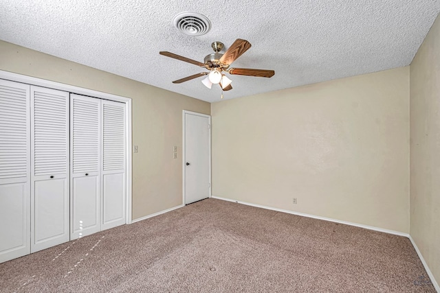 unfurnished bedroom with ceiling fan, carpet, a textured ceiling, and a closet